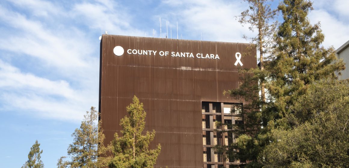 A tall county government building with trees in the foreground