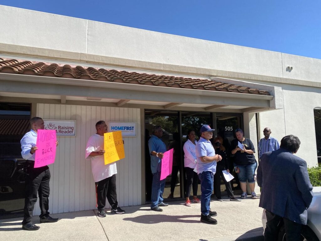 Group of advocates, NAACP representatives, and former HomeFirst employees rallying in front of the HomeFirst offices