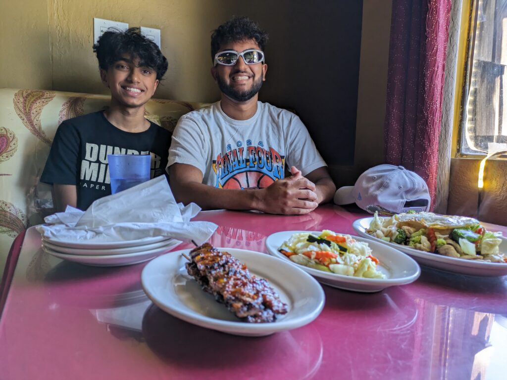 Two men sit at a restaurant table with Cambodian dishes