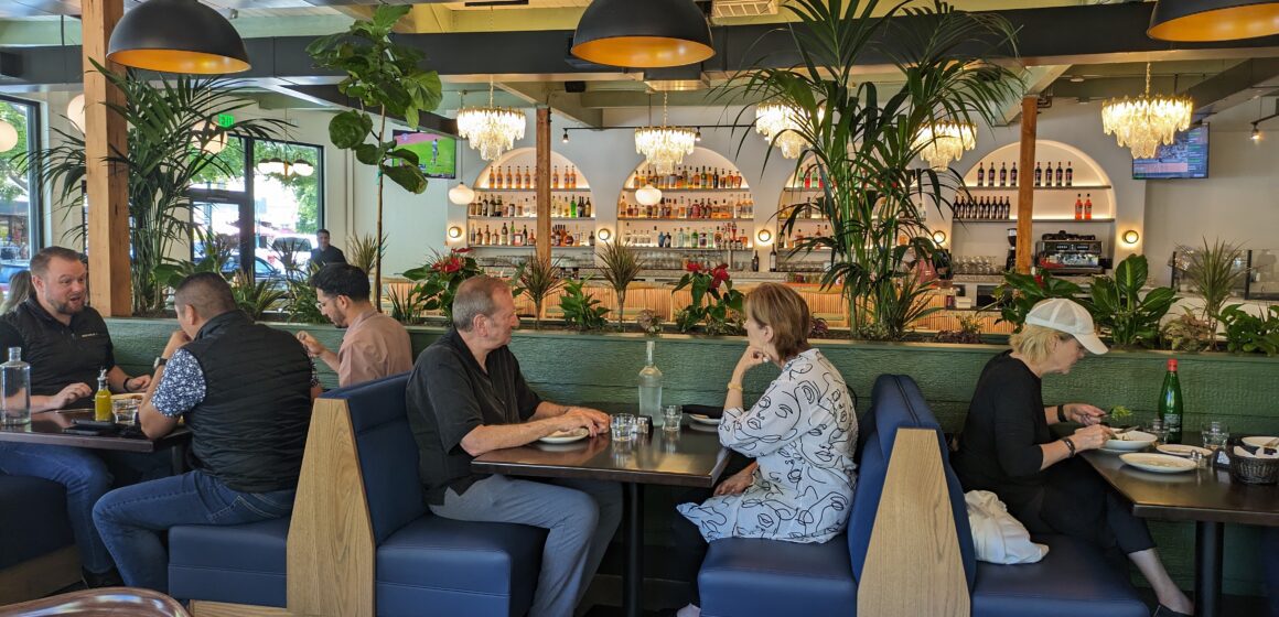 The interior of Doppio Zero, with people sitting at booths and a bar in the background