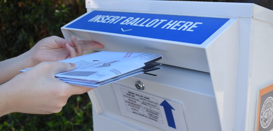 A voter drops off ballots in a neighborhood ballot drop box. Photo by Lorraine Gabbert.