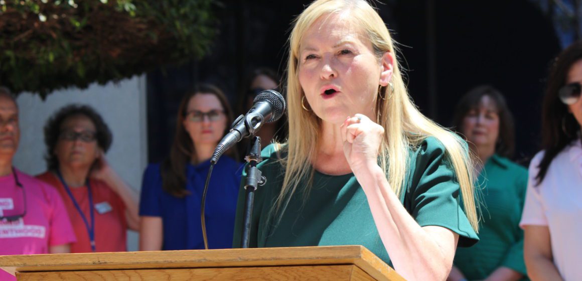 A woman speaks into a microphone at a podium