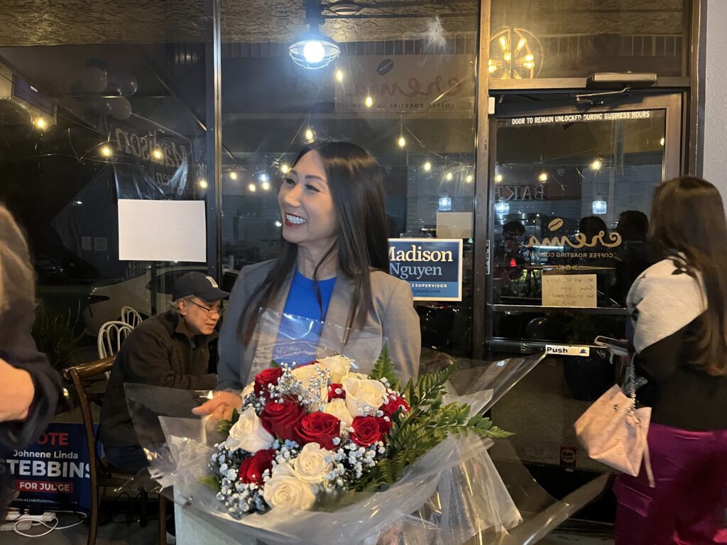 A woman stands inside holding a bouquet of flowers.