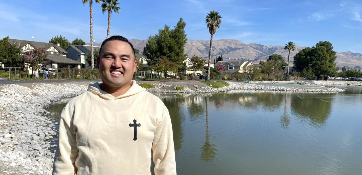 Former Milpitas Mayor Rich Tran standing in front of a small lake with the Milpitas Hills in the background