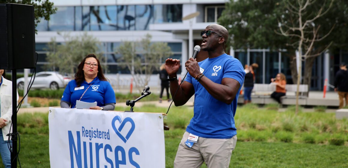 A registered nurse speaks into a microphone at a rally for better pay and working conditions in San Jose.