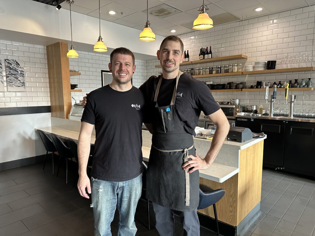 Two men stand inside a restaurant.