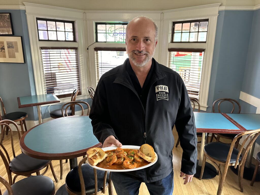 A man holds a plate of food inside a restaurant