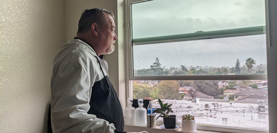 Man looks out his apartment window