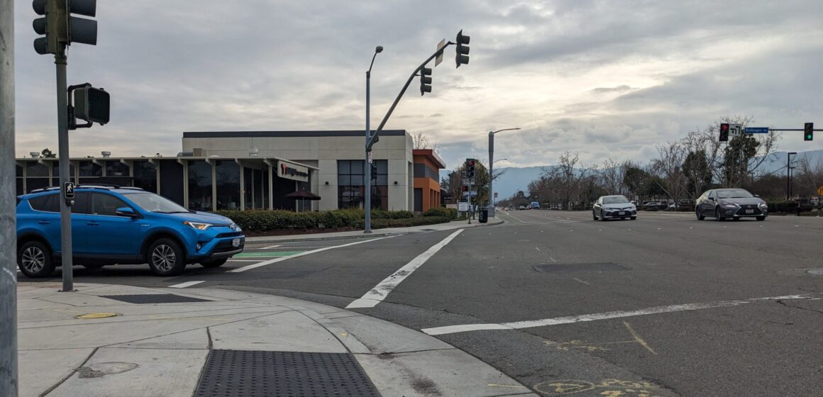 An intersection along Bollinger Road in Cupertino with cars and a stoplight.