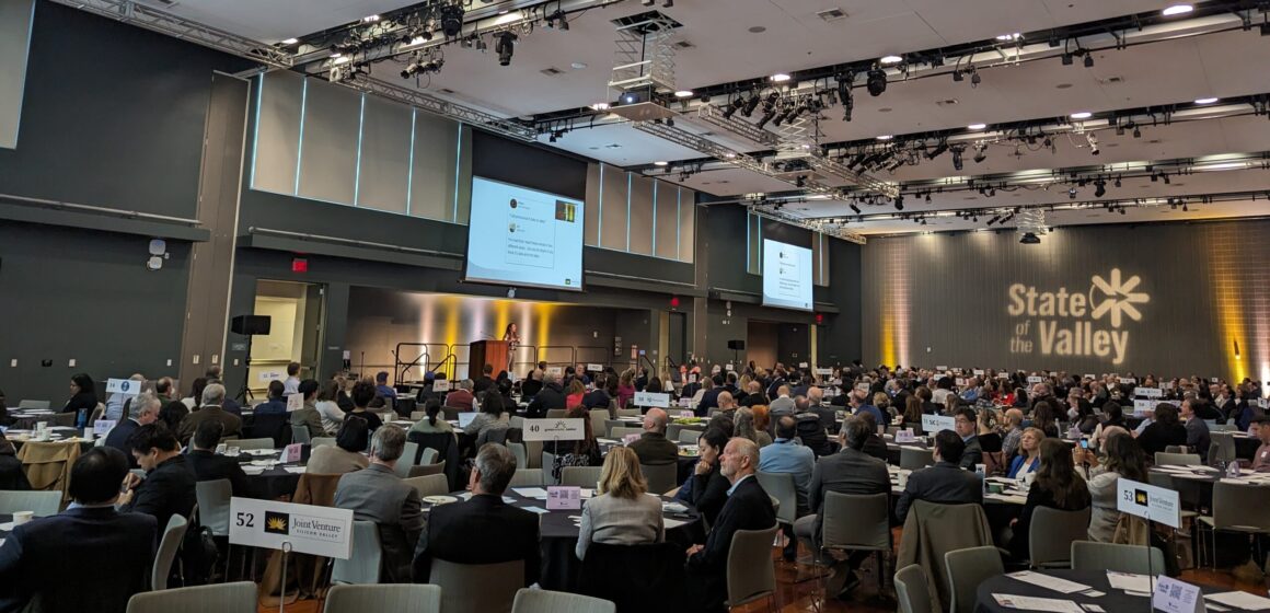 A convention room full of people at round tables