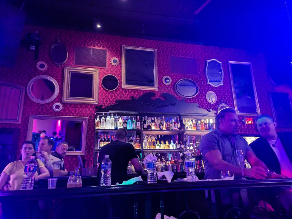 A bar in a nightclub, set against a wall of eclectic mirrors and patterned wallpaper