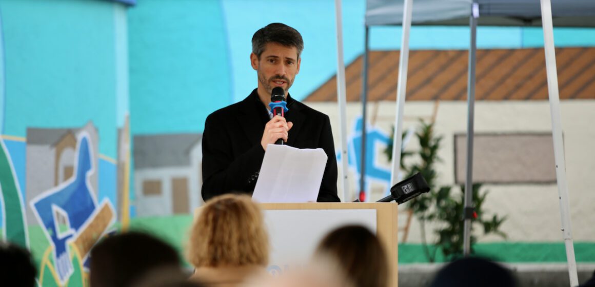 The mayor of San Jose standing at a podium holding a microphone