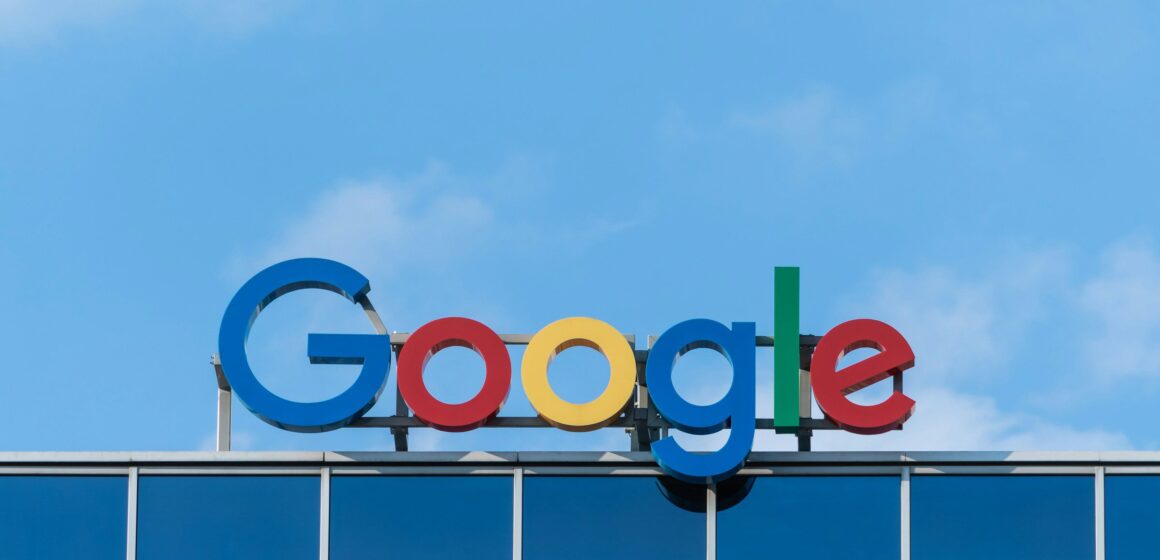 A Google sign on top of a building with blue sky above.