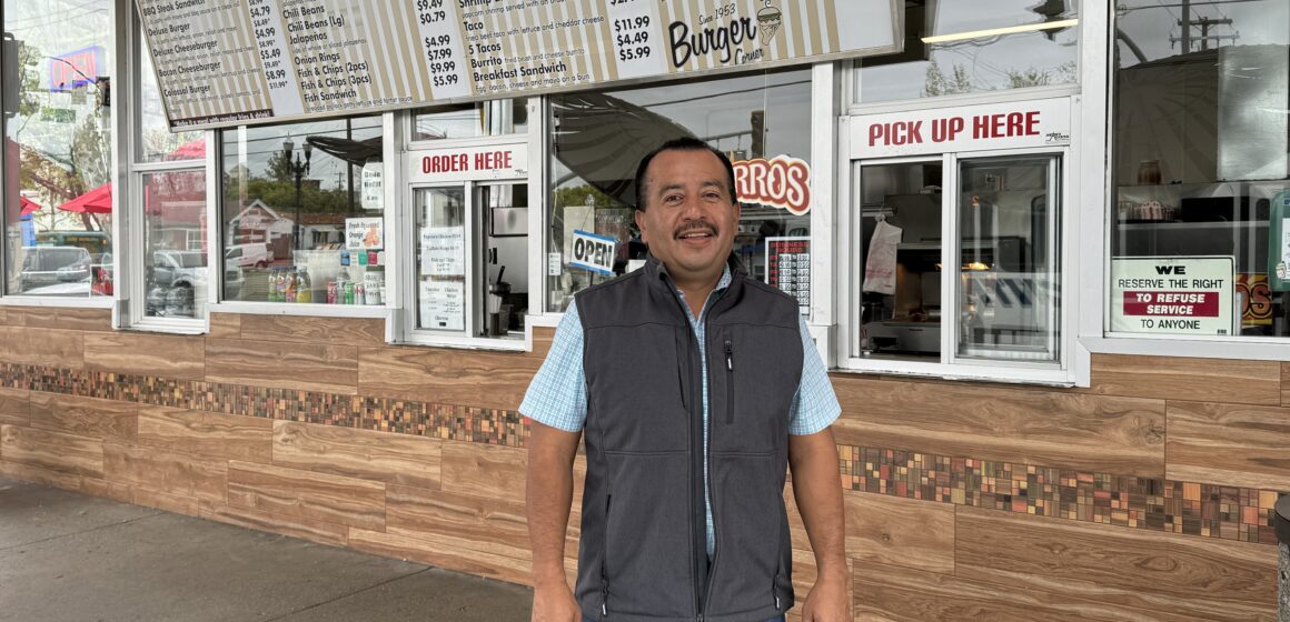 A man standing in front of a walk up burger window in San Jose