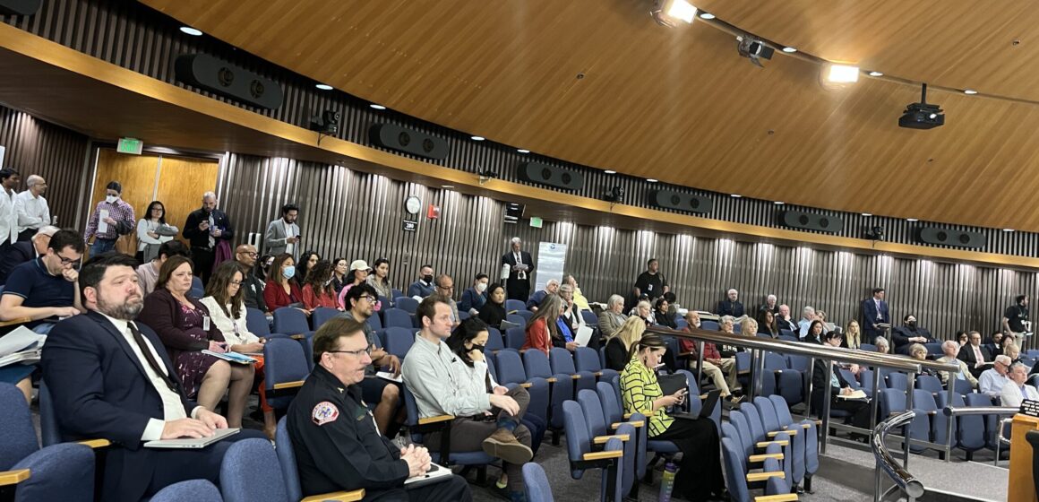 A crowd of people sit in the chambers of the Santa Clara County Board of Supervisors during a public meeting