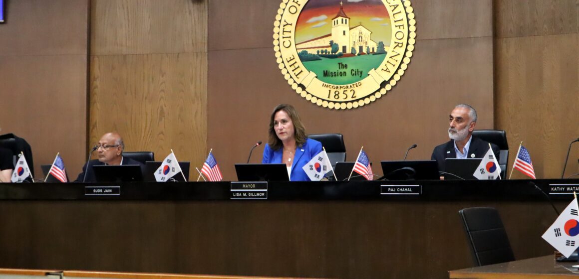 Santa Clara City Council chambers, centered on a Caucasian brunette woman in a blue blazer with the name tag "Mayor, Lisa M. Gillmor"